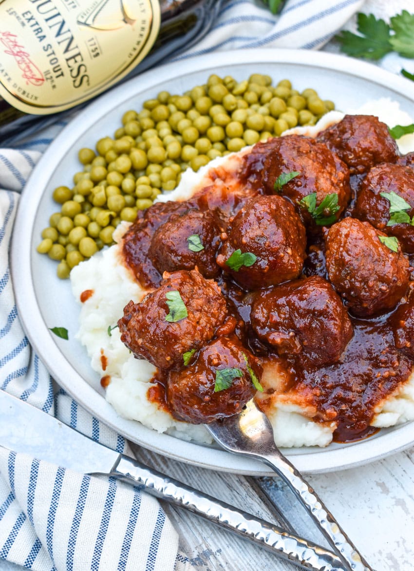 slow cooker guinness meatballs over mashed potatoes on a white plate