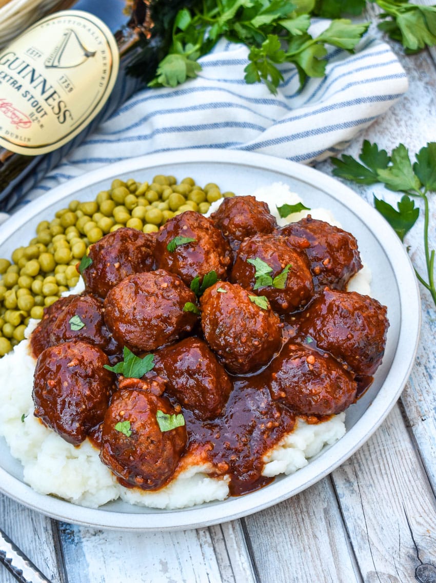 slow cooker guinness meatballs over mashed potatoes on a white plate