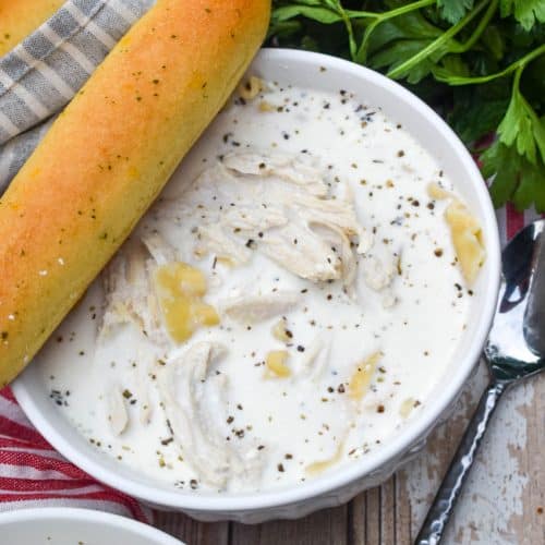 WHITE LASAGNA SOUP IN A WHITE BOWL WITH A BREADSTICK RESTING ON THE SIDE