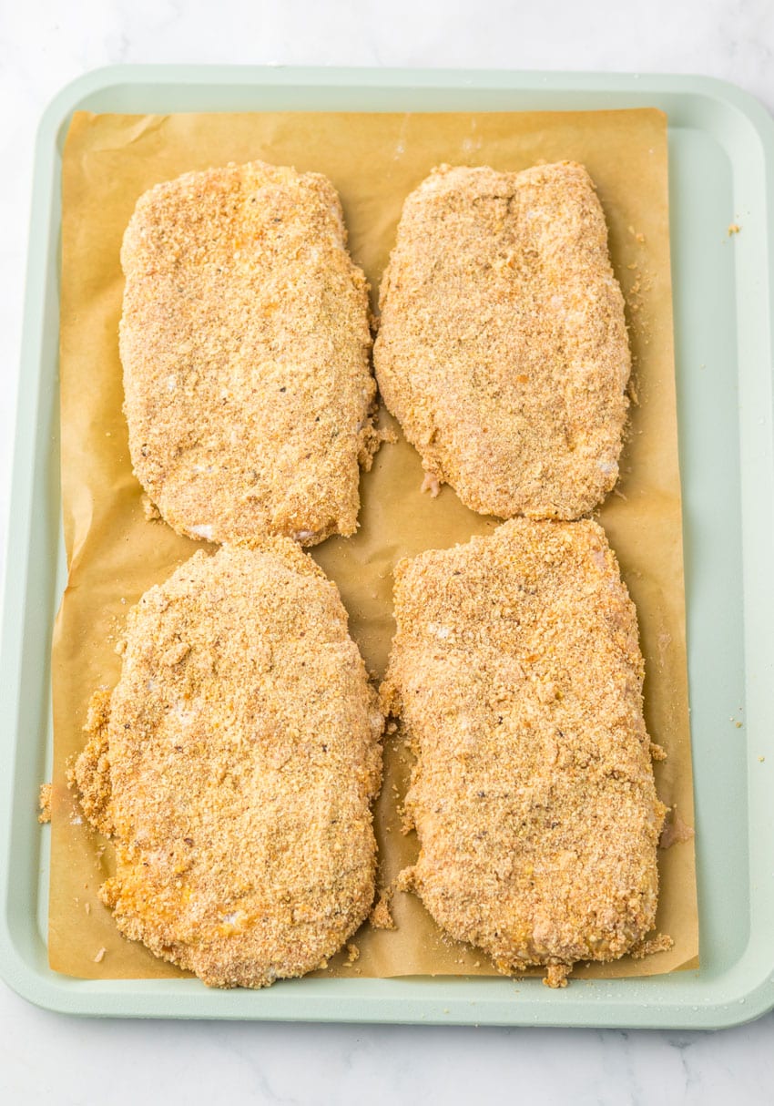 four homemade breaded chicken patties on a sheet of brown parchment paper