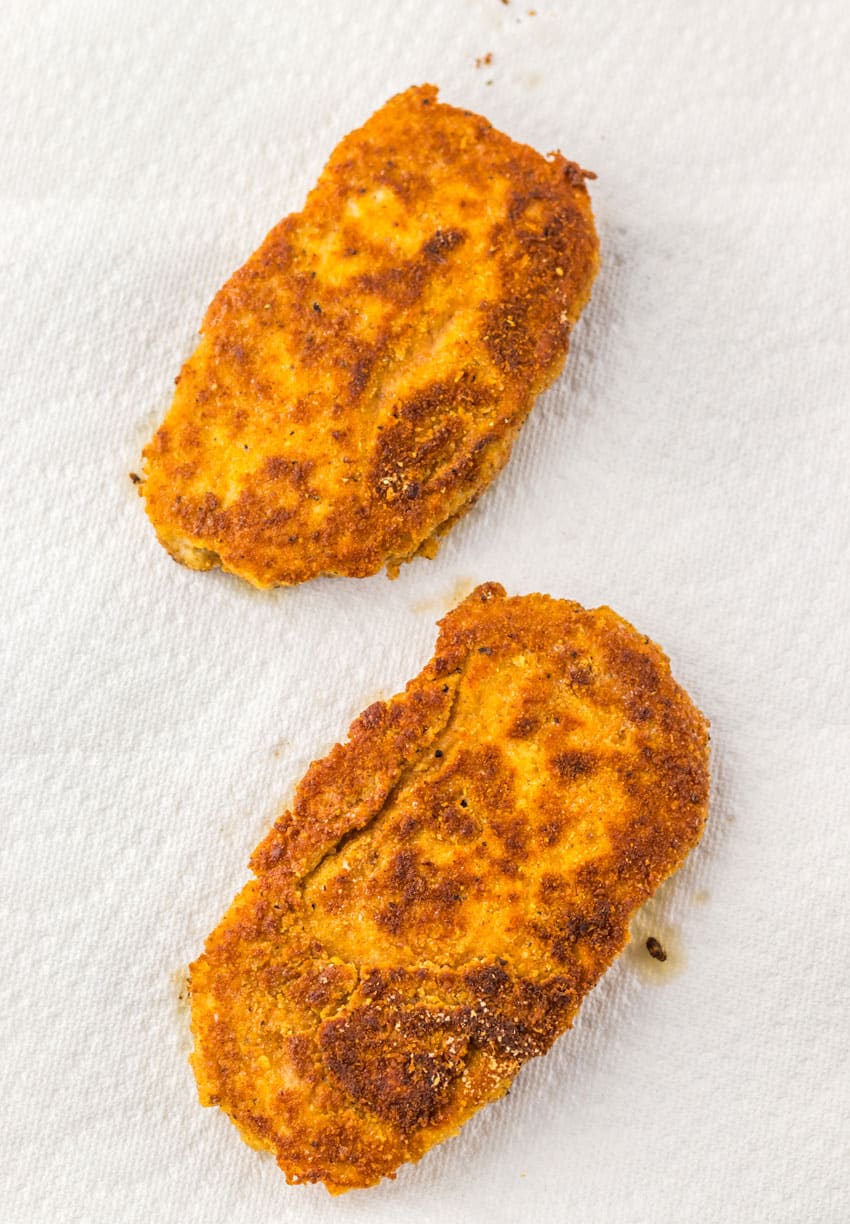 two fried chicken patties on white paper towels
