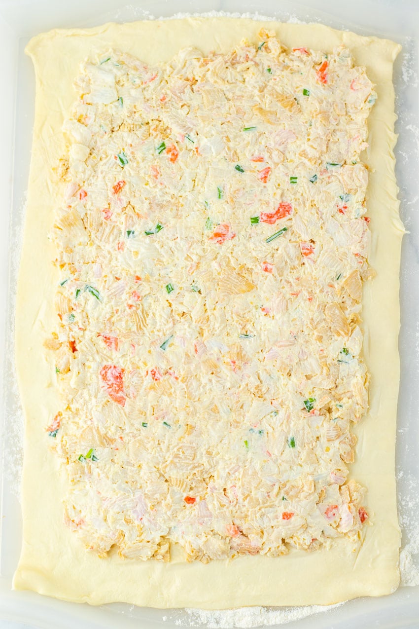 crab rangoon filling spread out over a rectangular sheet of pie crust