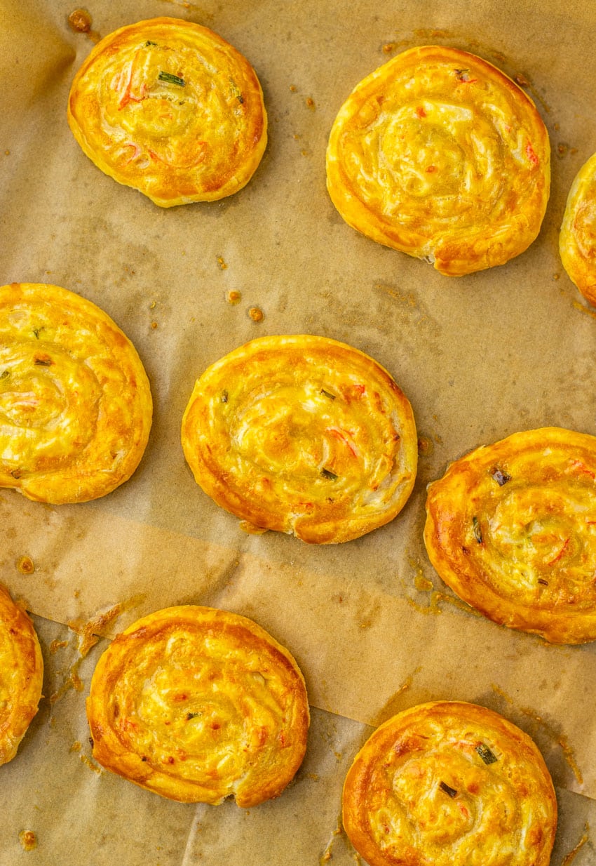 baked crab rangoon pinwheels on a parchment paper lined baking sheet