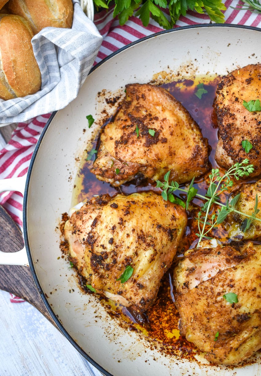 crispy italian chicken thighs in a large white cast iron skillet
