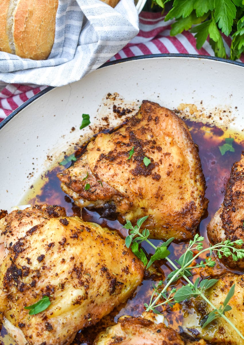 crispy italian chicken thighs in a large white cast iron skillet