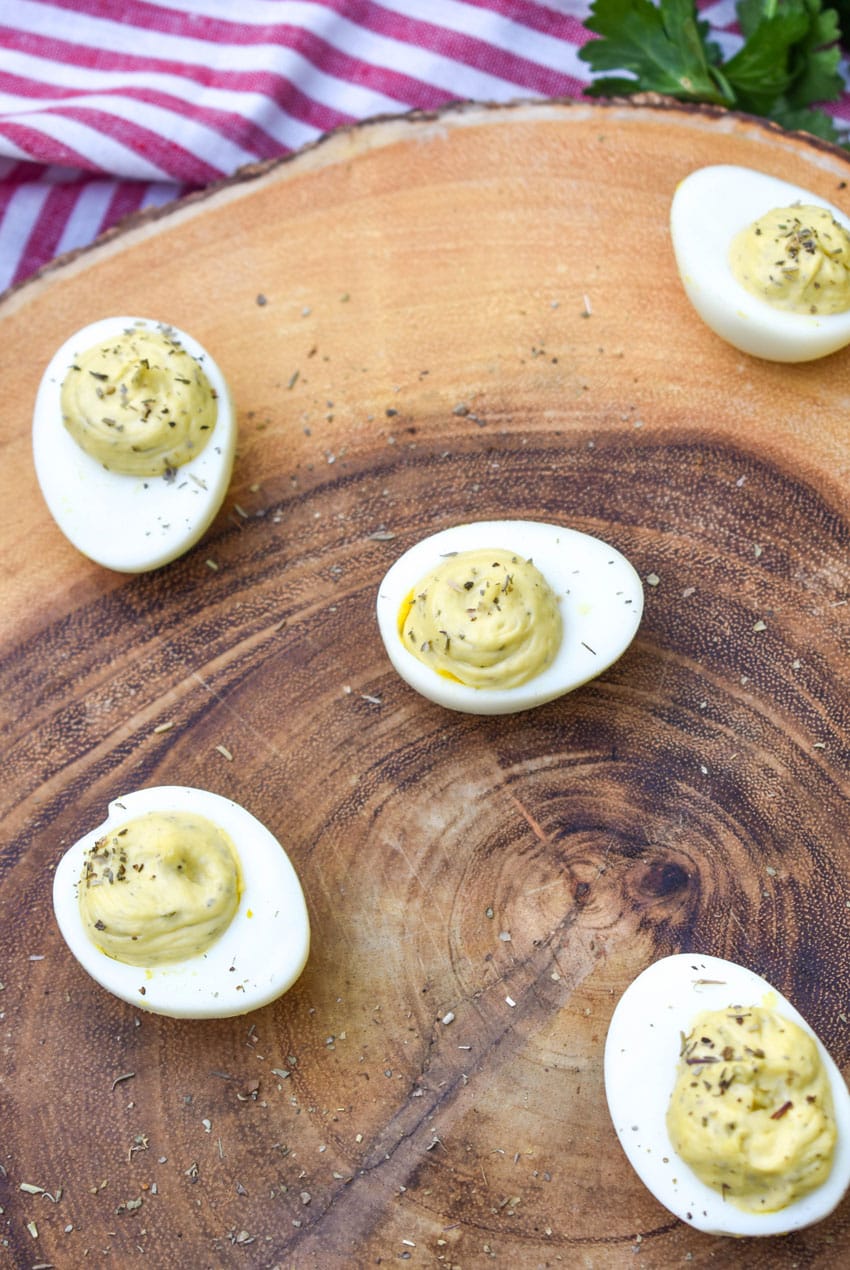 italian caper deviled eggs on a wooden cutting board