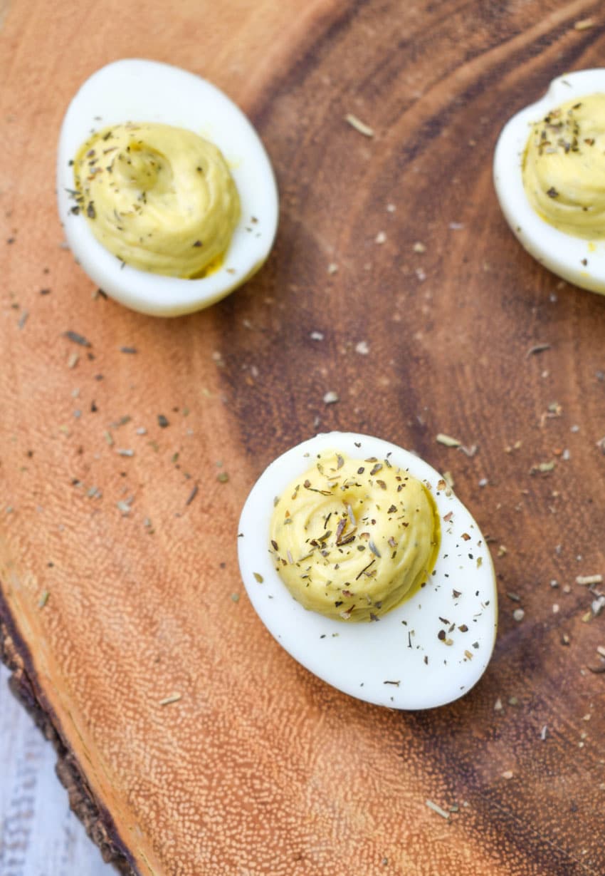italian caper deviled eggs on a wooden cutting board