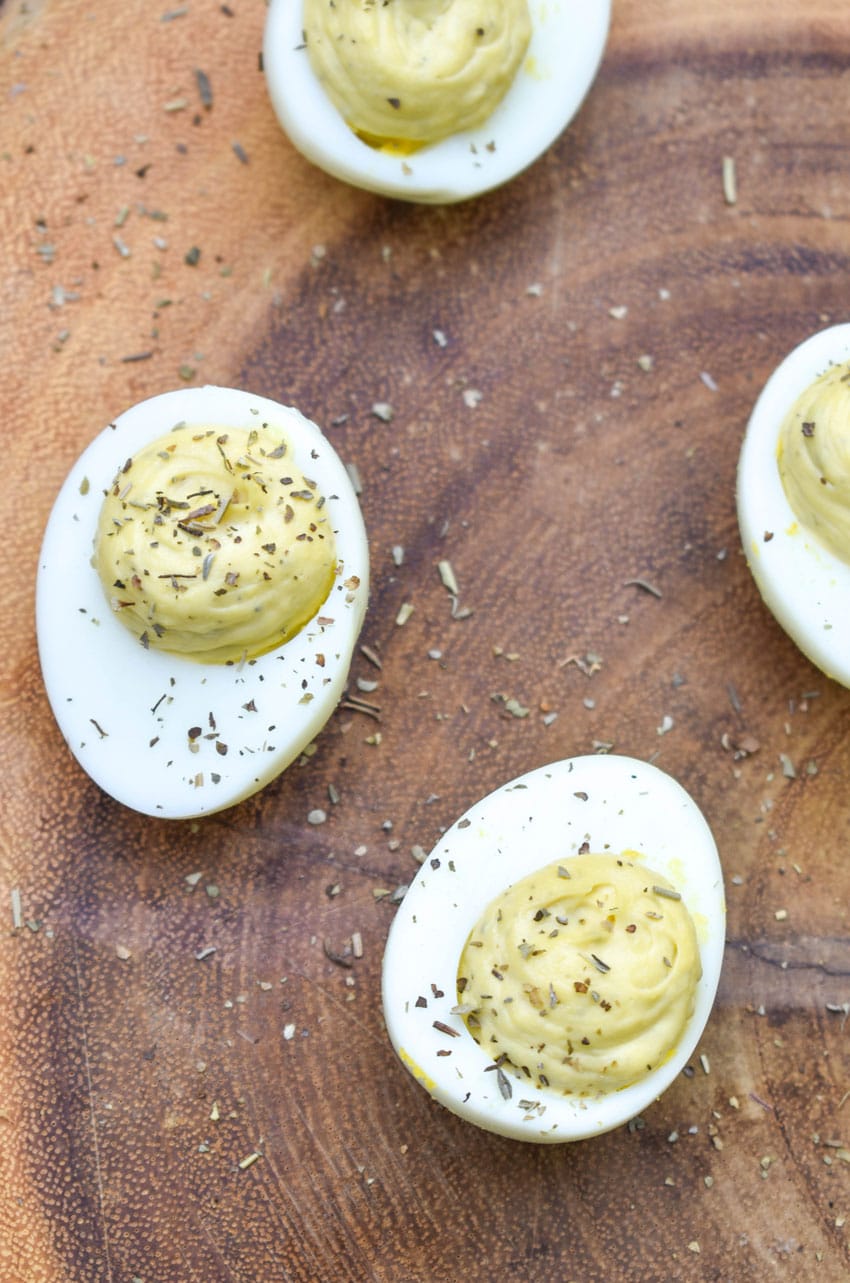 italian caper deviled eggs on a wooden cutting board