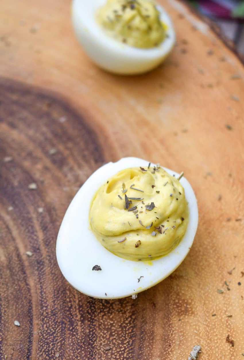 italian caper deviled eggs on a wooden cutting board