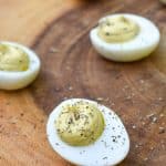 italian caper deviled eggs on a wooden cutting board