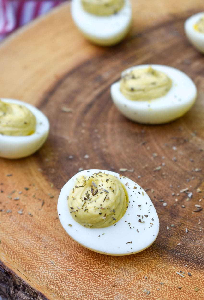 italian caper deviled eggs on a wooden cutting board
