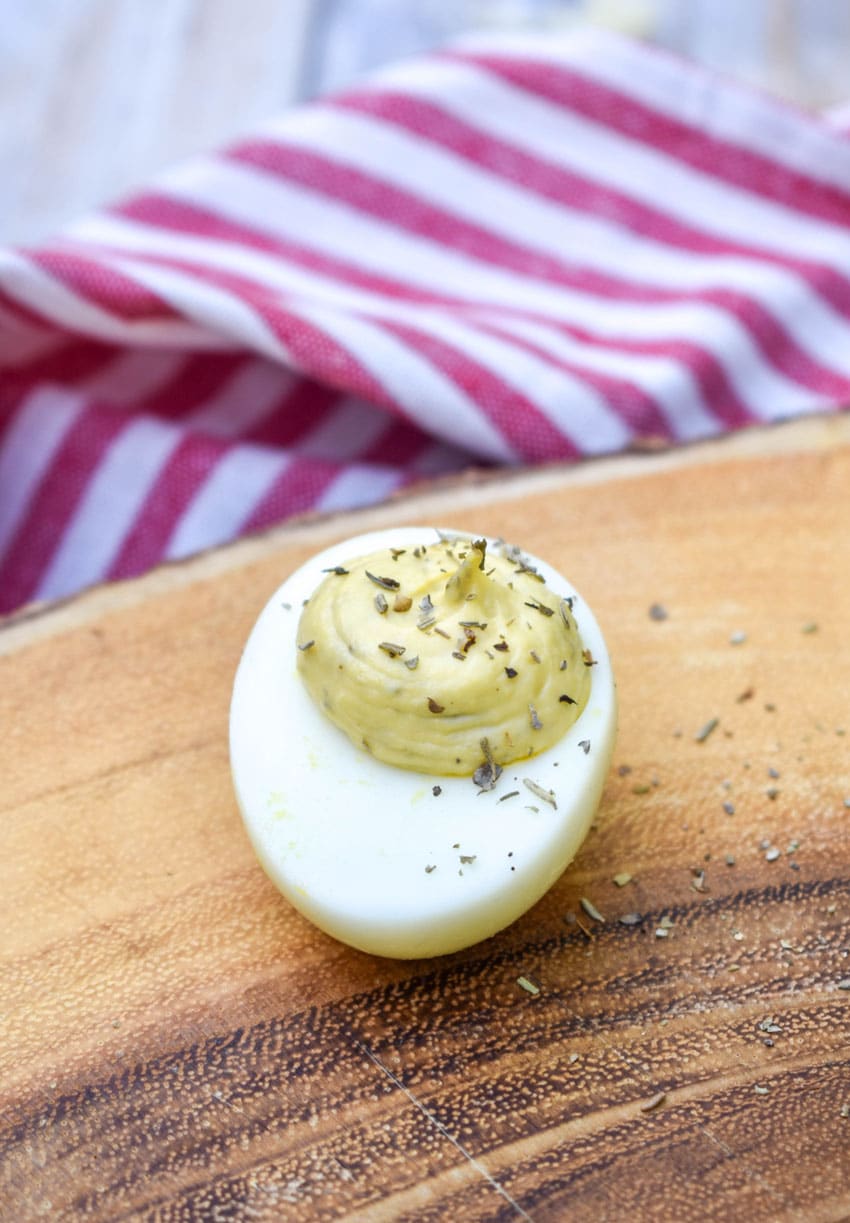 italian caper deviled eggs on a wooden cutting board