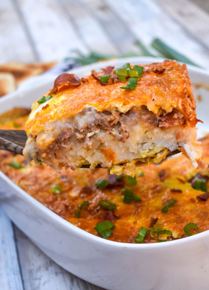 a spatula holding up a slice of a loaded hashbrown casserole