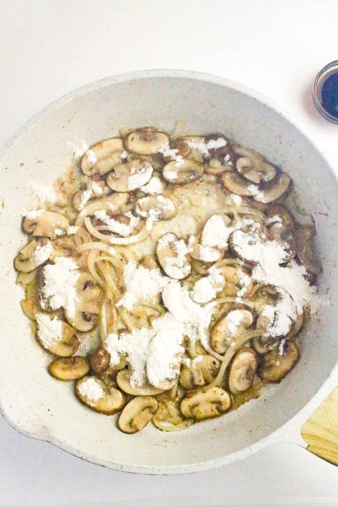 sliced mushrooms and flour in butter in a white skillet