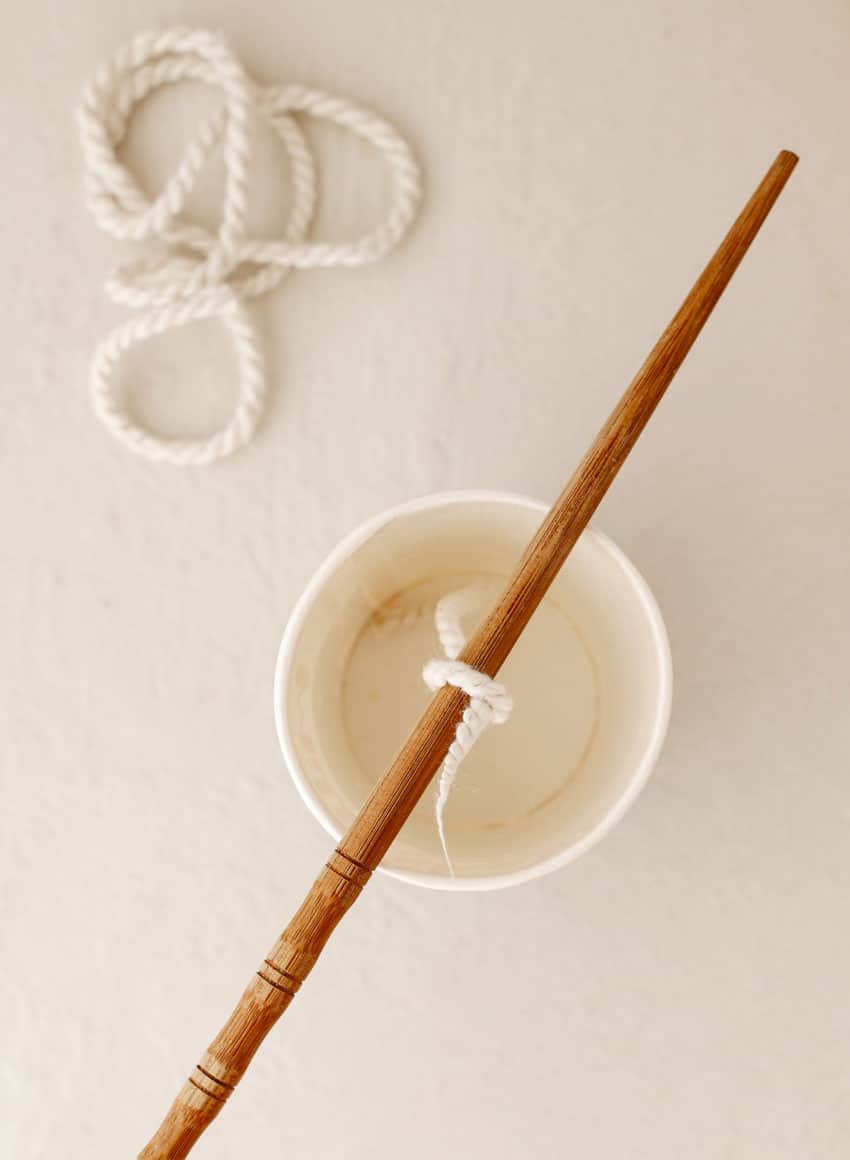 a food grade white wick tired to a chopstick resting on top of a paper cup