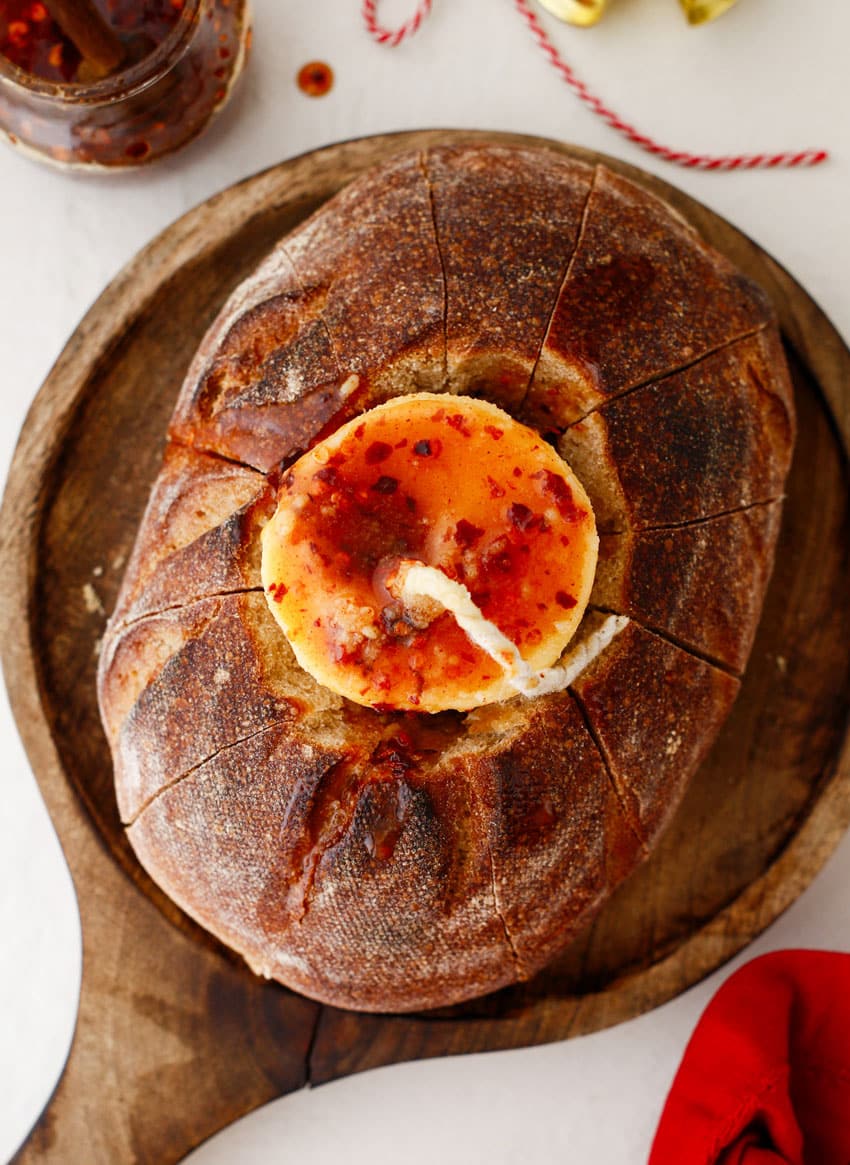 a lit hot honey butter candle in a hollowed out loaf of bread resting on a wooden cutting board