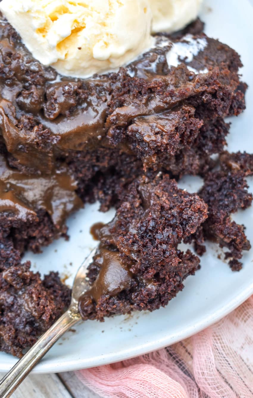 A FORK SCOOPING HOMEMADE CHOCOLATE LAVA CAKE OFF A GRAY PLATE