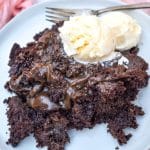 slow cooker chocolate lava cake topped with two scoops of melting vanilla ice cream on a gray plate