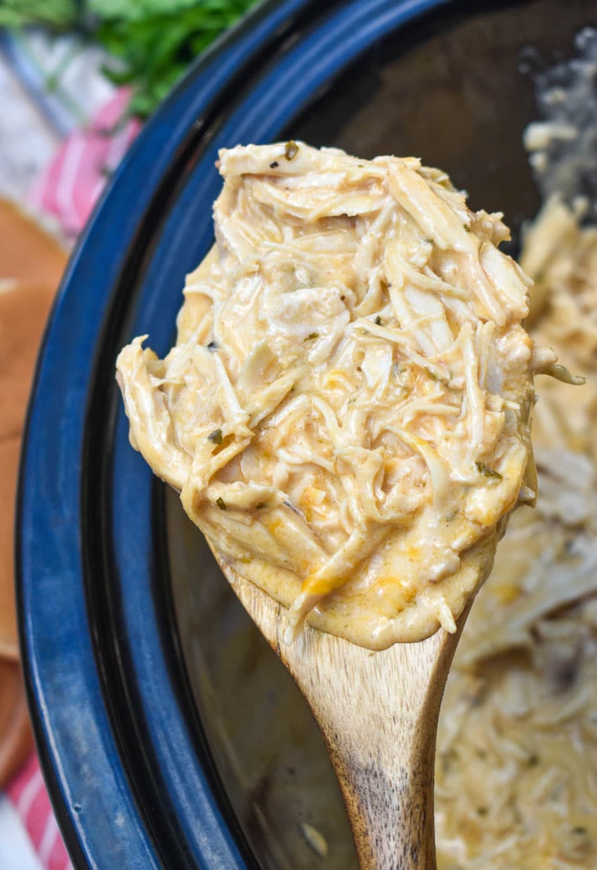 a wooden spoon holding up a scoop of shredded garlic parmesan chicken