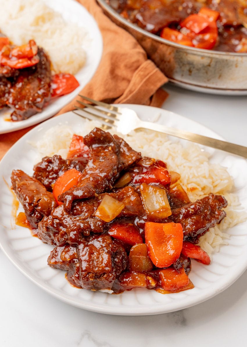 homemade beijing beef next to steamed white rice on a white plate
