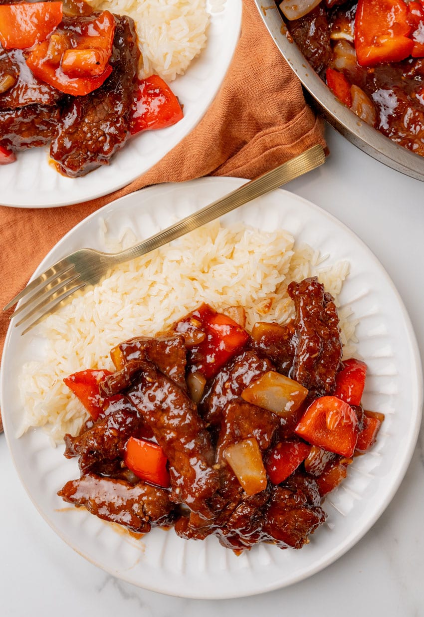homemade beijing beef next to steamed white rice on a white plate