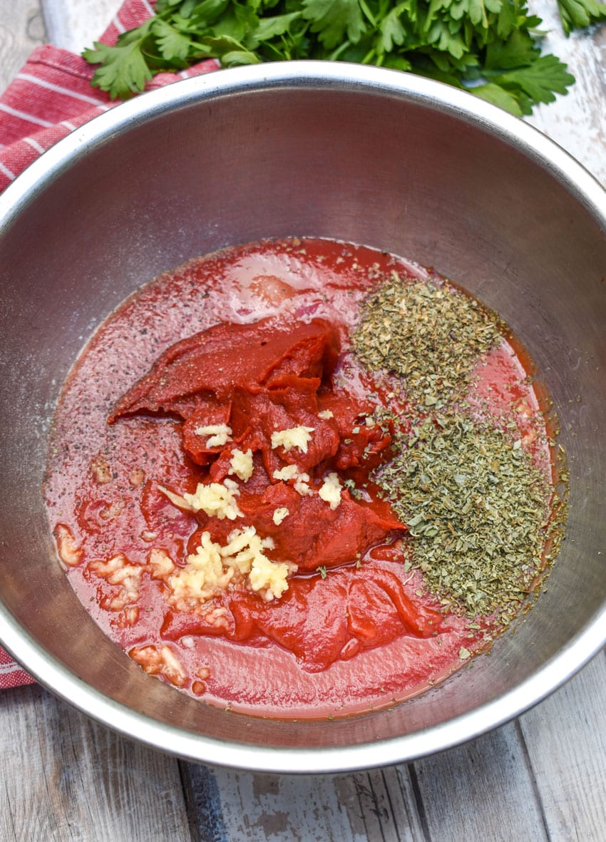 homemade pizza sauce ingredients in a large metal mixing bowl