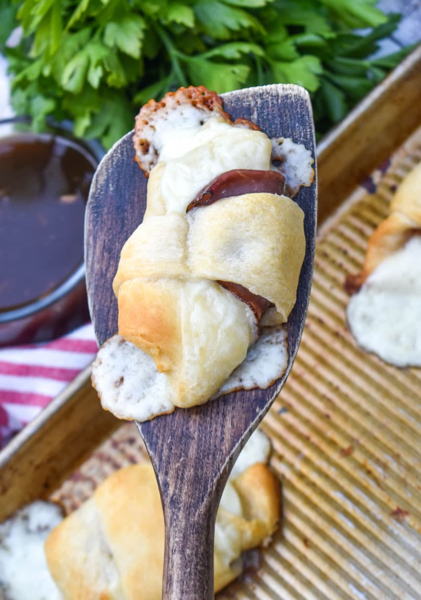 a wooden spatula holding up a french dip crescent roll