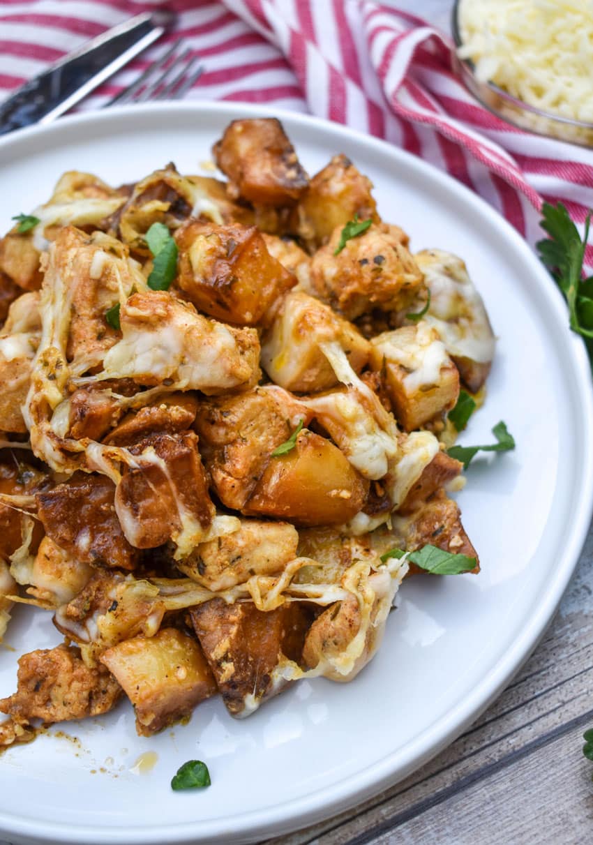 cheesy garlic parmesan chicken and potatoes on a white plate