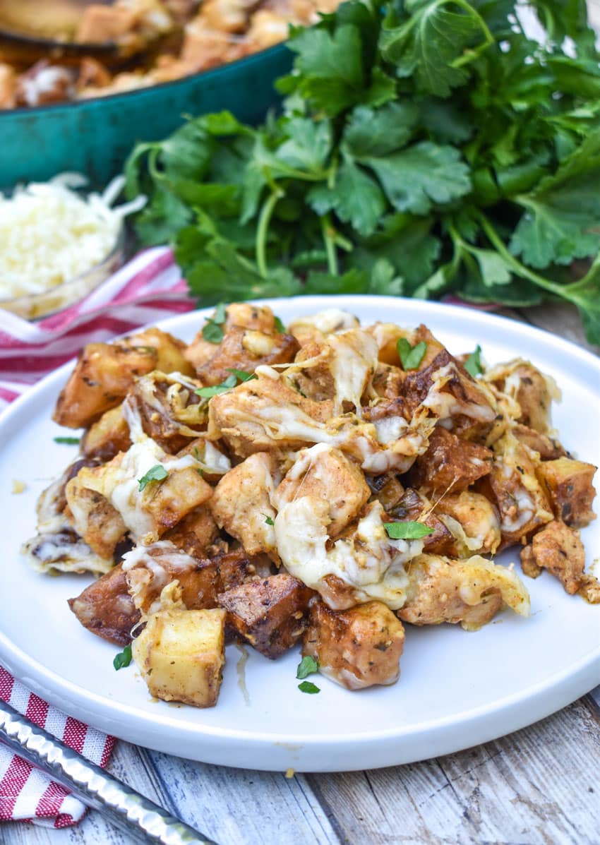cheesy garlic parmesan chicken and potatoes on a white plate