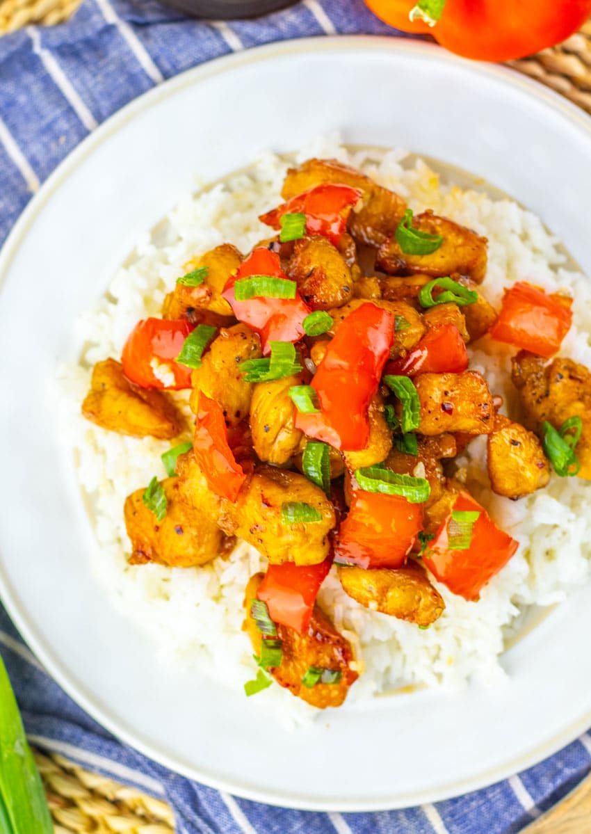 HONEY PEPPER CHICKEN OVER STEAMED WHITE RICE ON A WHITE PLATE