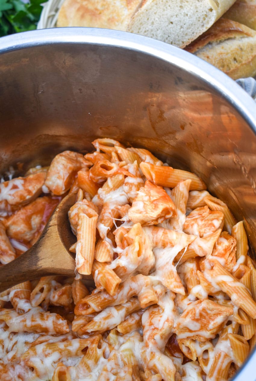 a wooden spoon scooping chicken parmesan pasta out of an instant pot