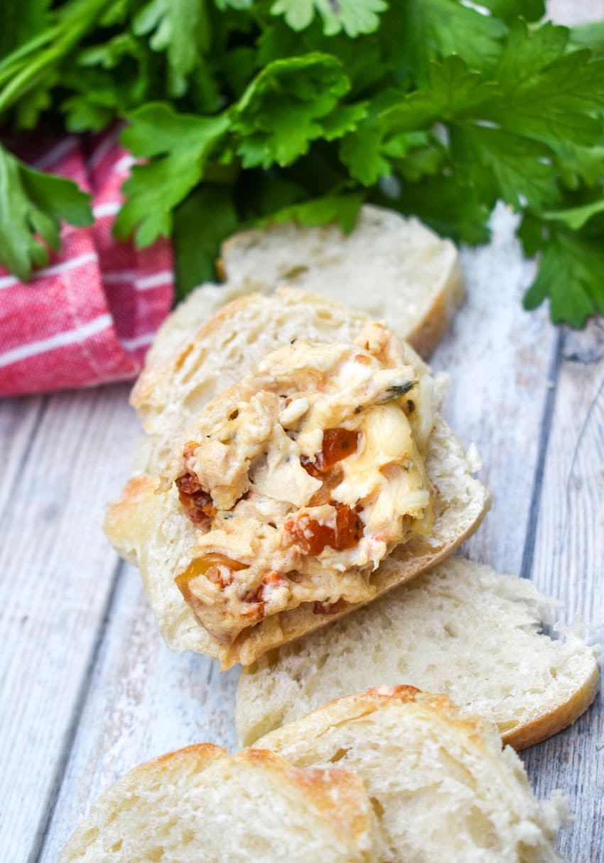 a marry me chicken dip topped slice of baguette bread resting on a wooden table