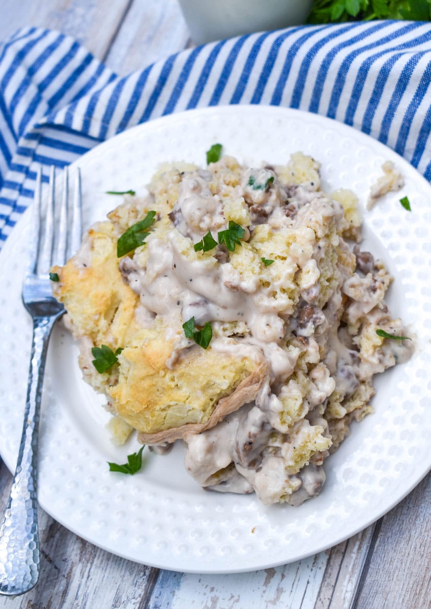 biscuits and gravy skillet on a small white plate with a silver fork resting on the side