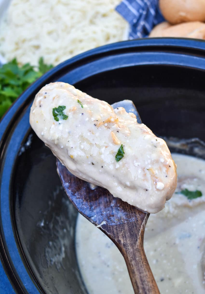 a wooden spatula lifting up a piece of slow cooker angel chicken