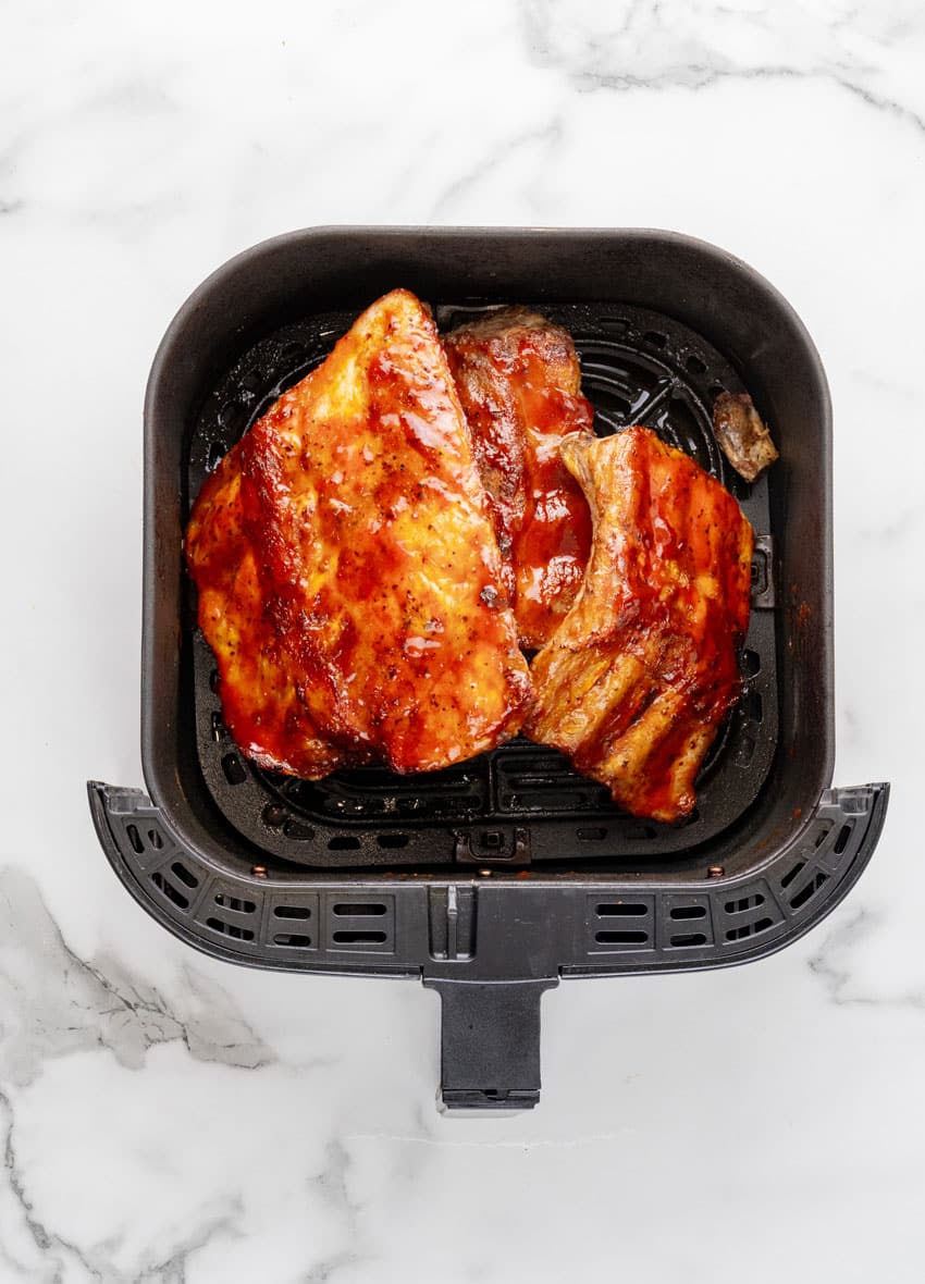 sauced ribs in the basket of an air fryer