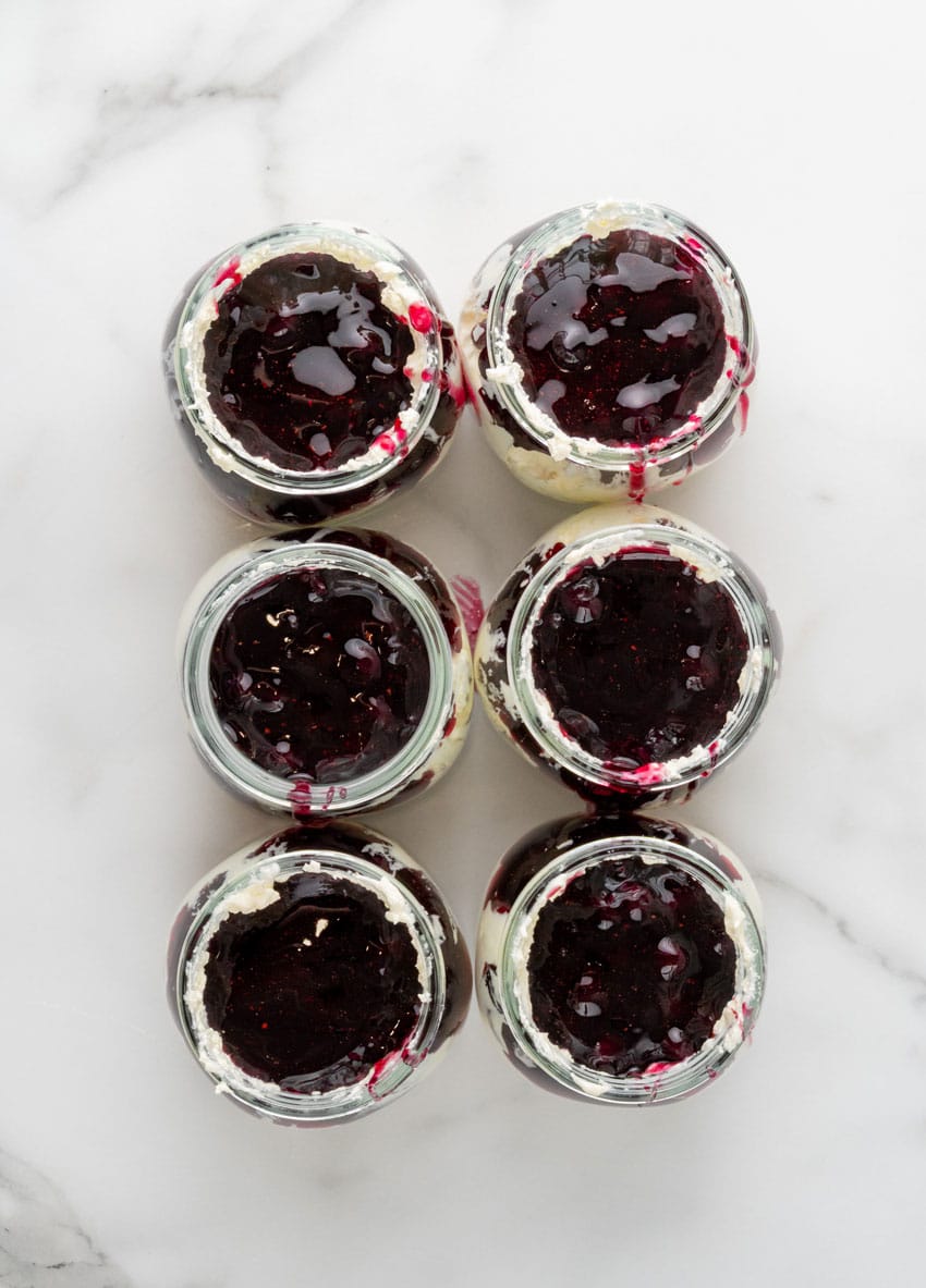 layers of cheesecake and blueberry filling in six small glass jars