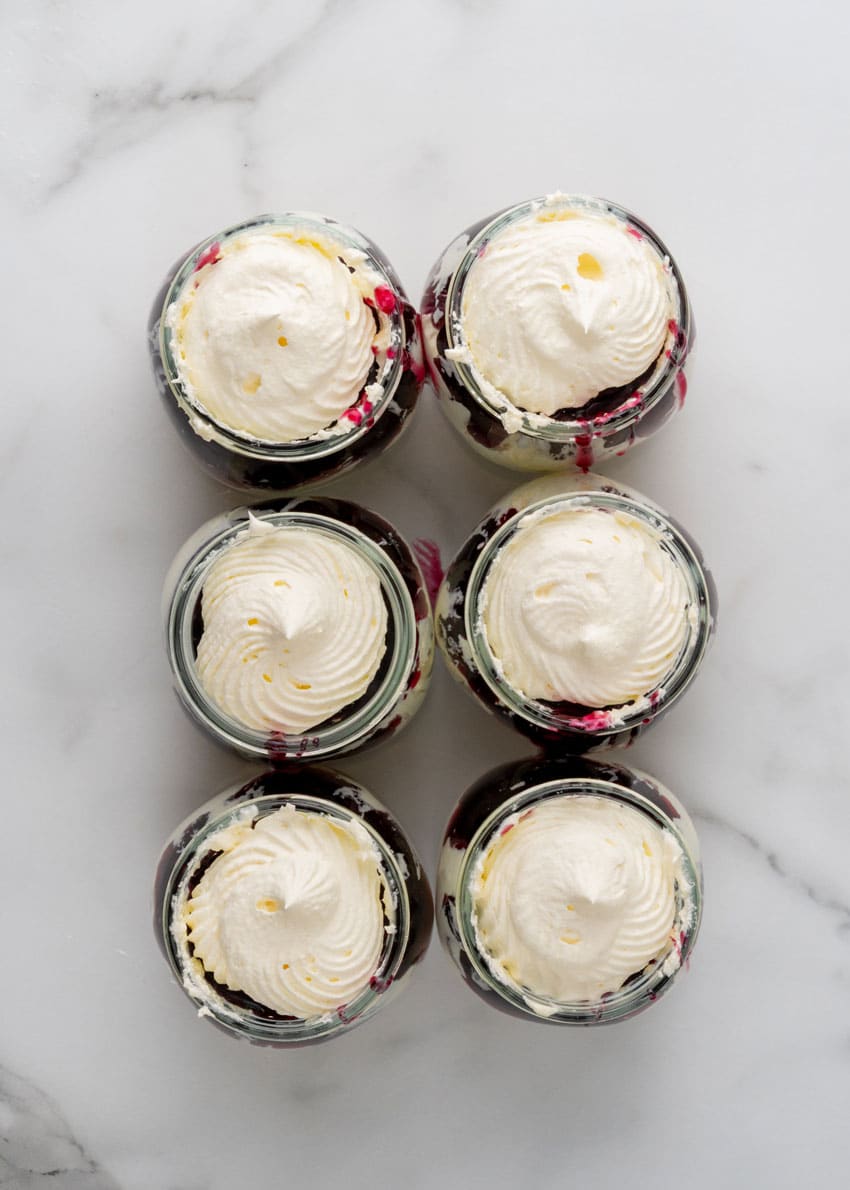 layers of cheesecake and blueberry filling in six small glass jars