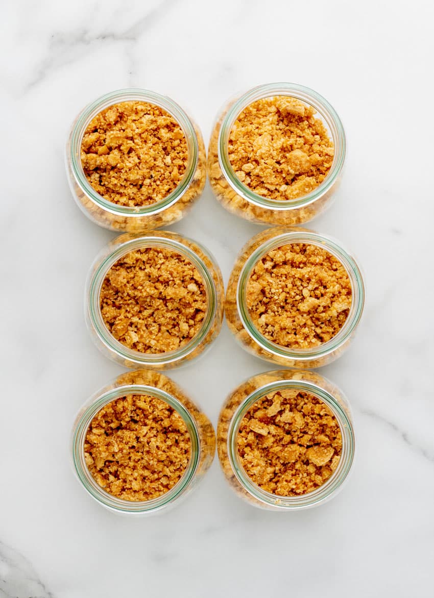graham cracker crumbs in six glass jars arranged in two rows