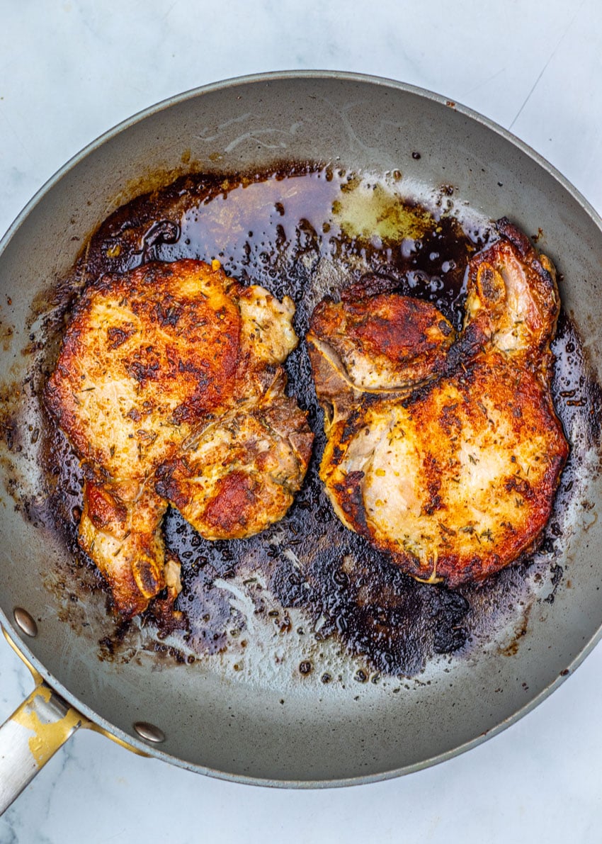 pan seared pork chops in a large black skillet