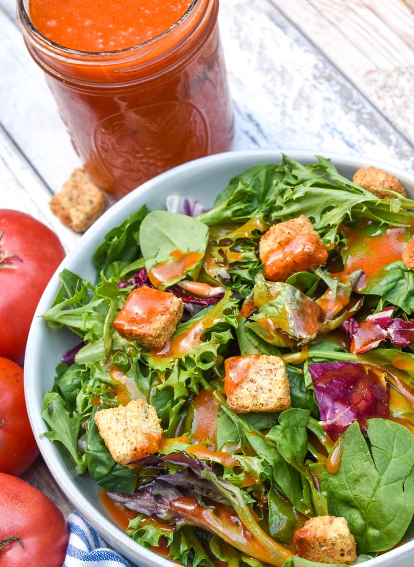 CONDENSED TOMATO SOUP SALAD DRESSING OVER A BED OF GREENS IN A SHallow WHITE BOWL