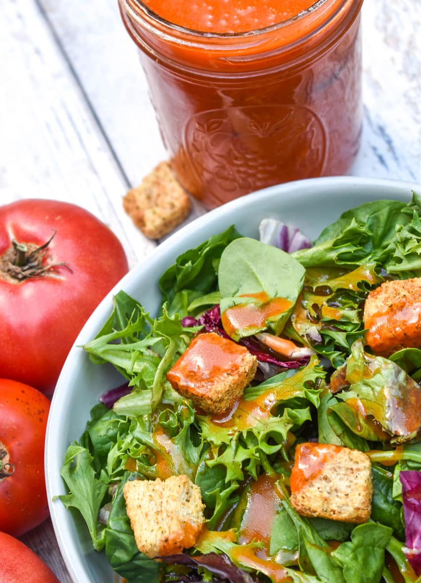CONDENSED TOMATO SOUP SALAD DRESSING OVER A BED OF GREENS IN A SHallow WHITE BOWL