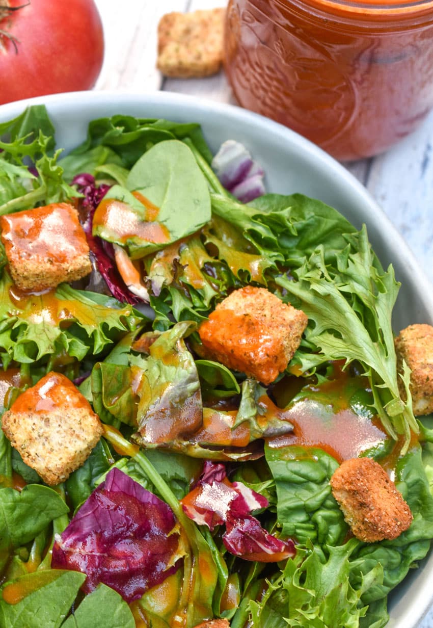 CONDENSED TOMATO SOUP SALAD DRESSING OVER A BED OF GREENS IN A SHallow WHITE BOWL