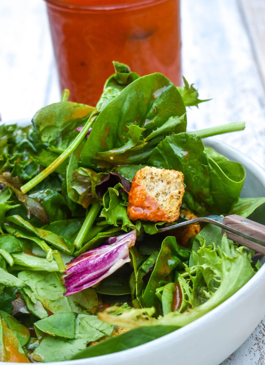 CONDENSED TOMATO SOUP SALAD DRESSING OVER A BED OF GREENS IN A SHallow WHITE BOWL
