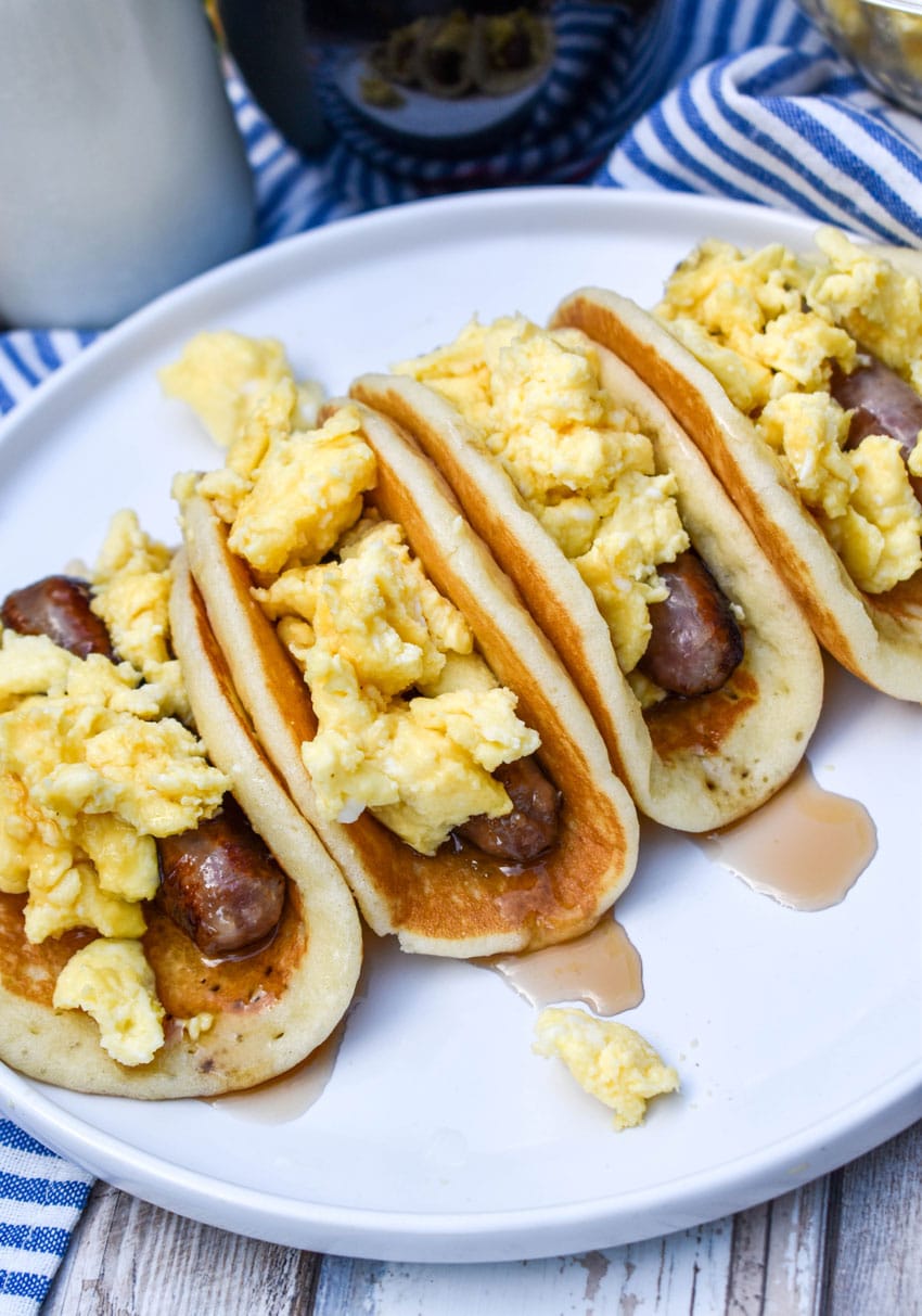 pancake breakfast tacos arranged in a row on a white serving plate