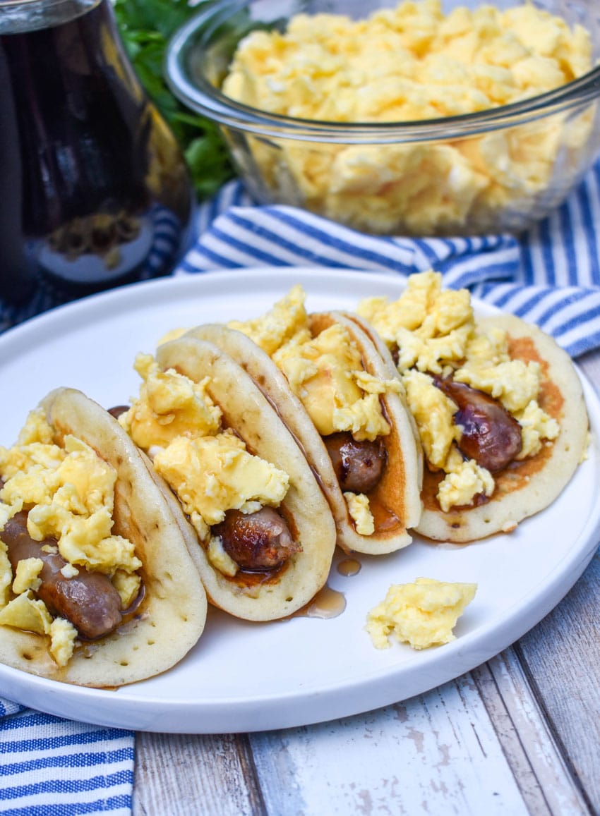 pancake breakfast tacos arranged in a row on a white serving plate