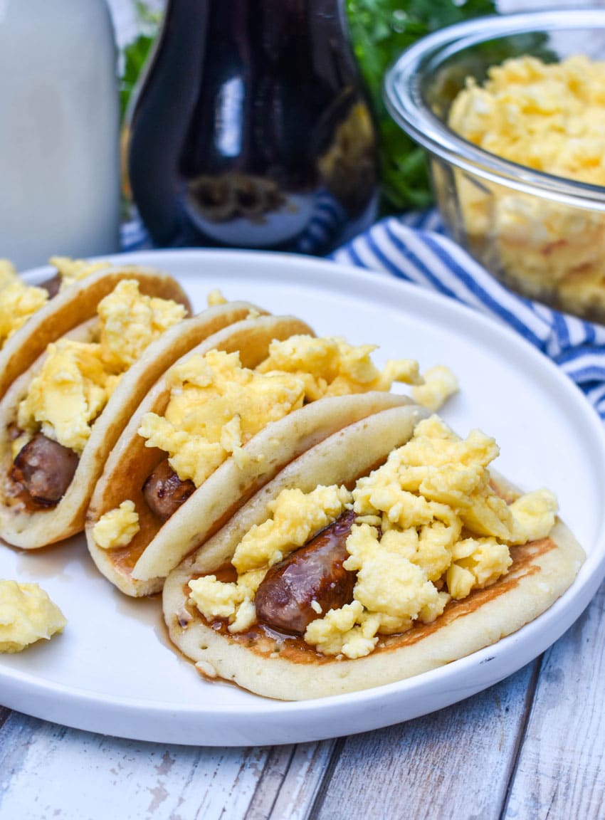 pancake breakfast tacos arranged in a row on a white serving plate