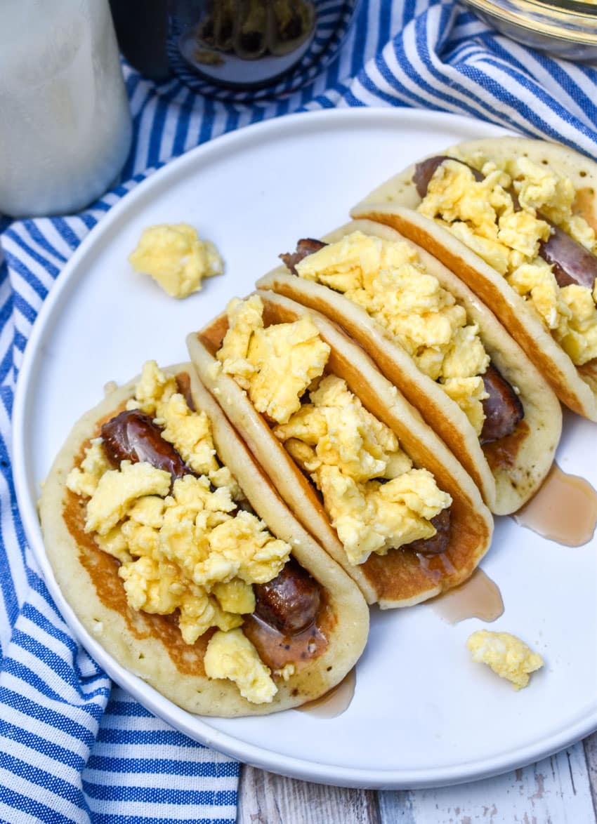 pancake breakfast tacos arranged in a row on a white serving plate
