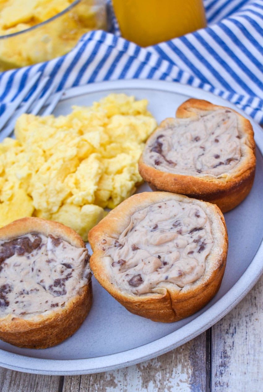 sausage gravy biscuit cups next to scrambled eggs on a white plate