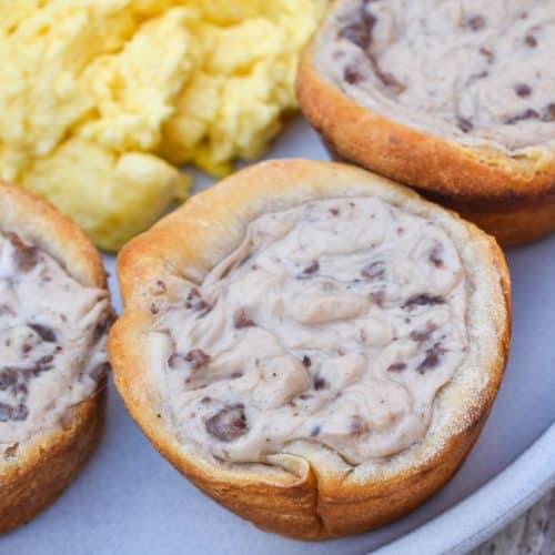sausage gravy biscuit cups next to scrambled eggs on a white plate