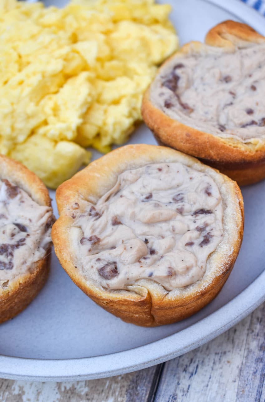 sausage gravy biscuit cups next to scrambled eggs on a white plate